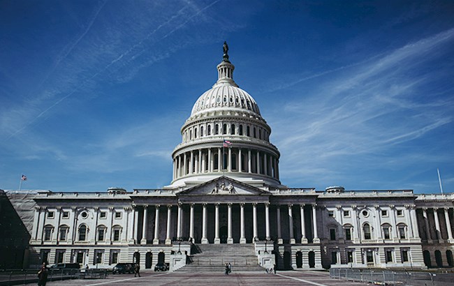Front view of the US Capitol building with bright blue sky