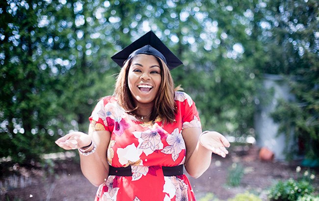 Happy female college student outside wearing graduation cap