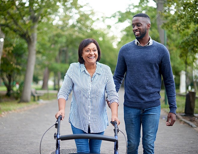 Man and senior woman using a walker outside walking down the street