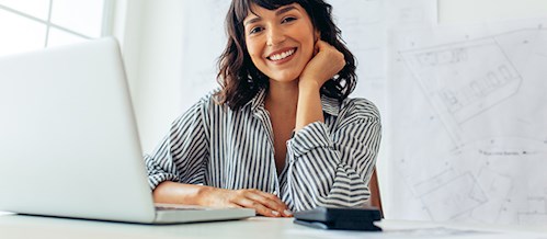 Smiling professional woman sitting behind open laptop