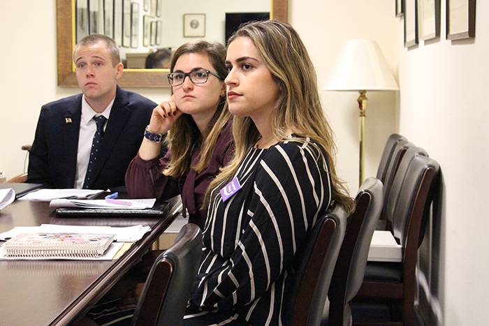 Two women and a man professionally dressed sitting at a conference table
