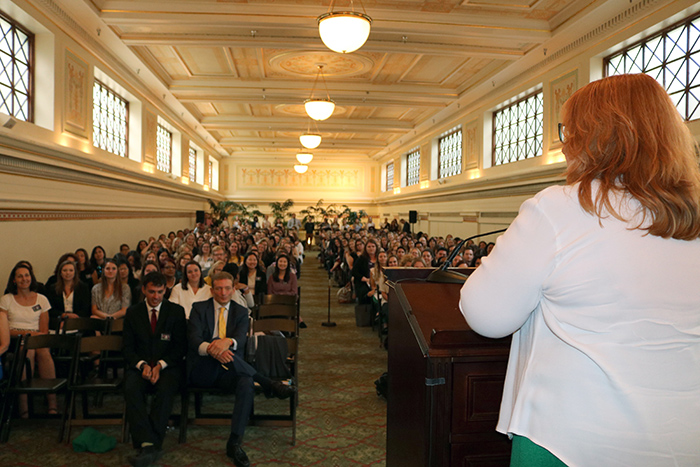 Woman at podium speaking to large crowd inside the Columbus Room