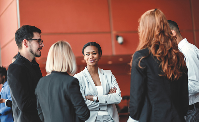Group of professional men and woman talking outside orange building