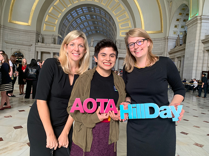 OT students smiling holding AOTA Hill Day sign inside building