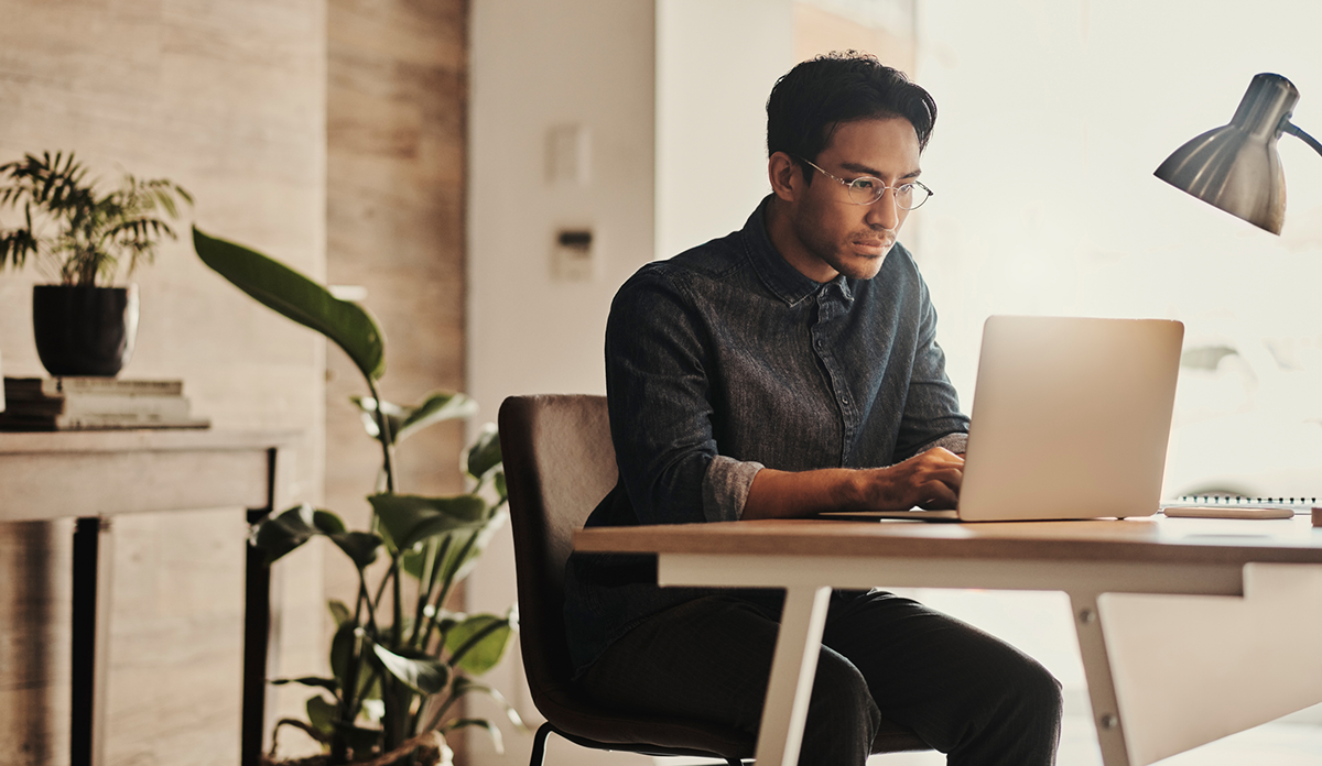 Man using laptop at a desk in an office setting