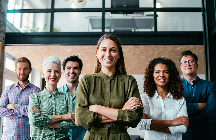 Diverse group of professional people smiling at camera with arms crossed