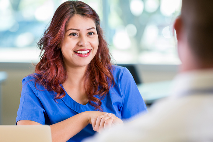 Smiling female healthcare working in blue scrubs talking with male colleague