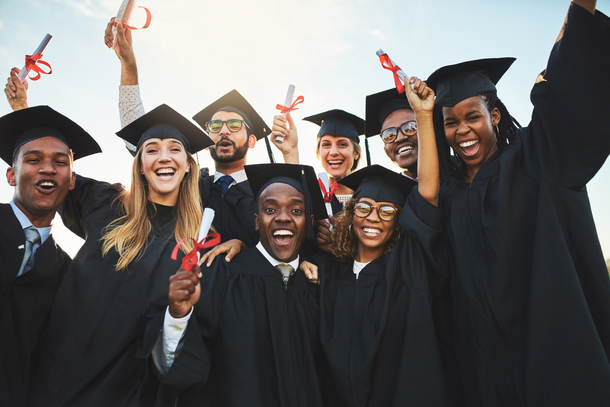 Group of smiling graduates in black caps and gowns.