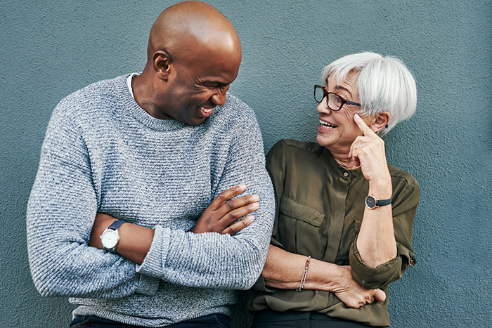 Smiling man and woman looking at each other talking in front of blue wall