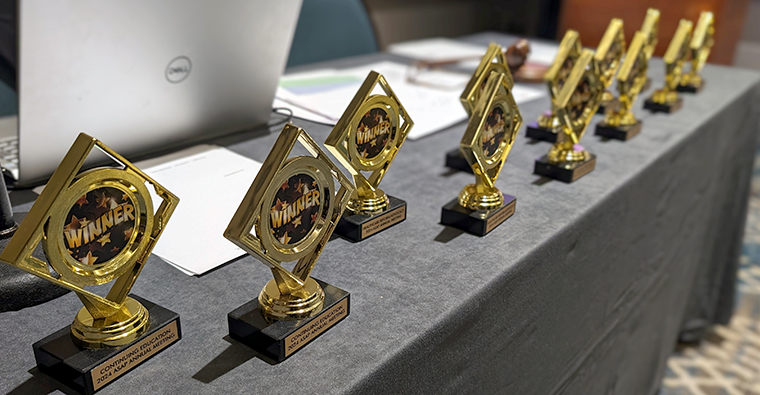 Trophies sitting in a row on a table with the word Winner written on them. 