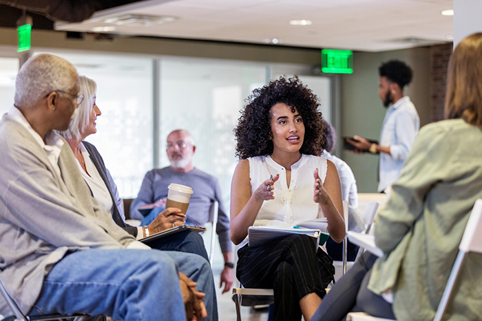 Group of men and woman sitting in chairs talking together in a circle