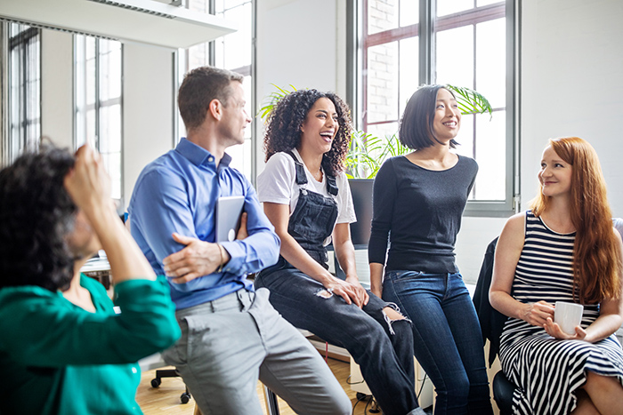 Group of men and woman laughing and talking inside office