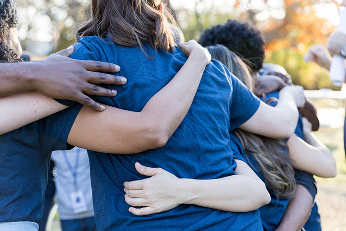 From behind shot of people huddled together with arms around each other