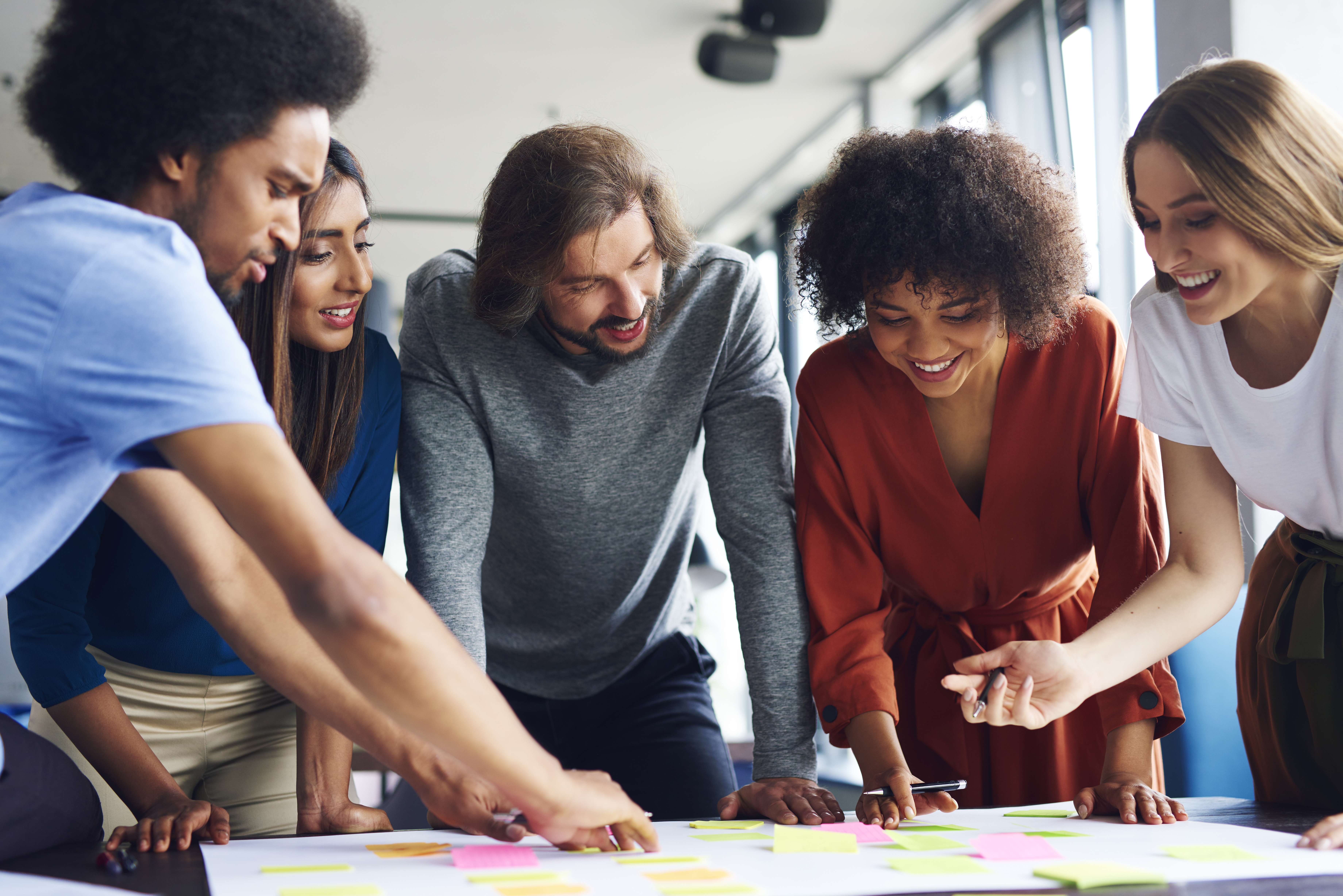 Diverse group of adults collaborating with post-its on table.