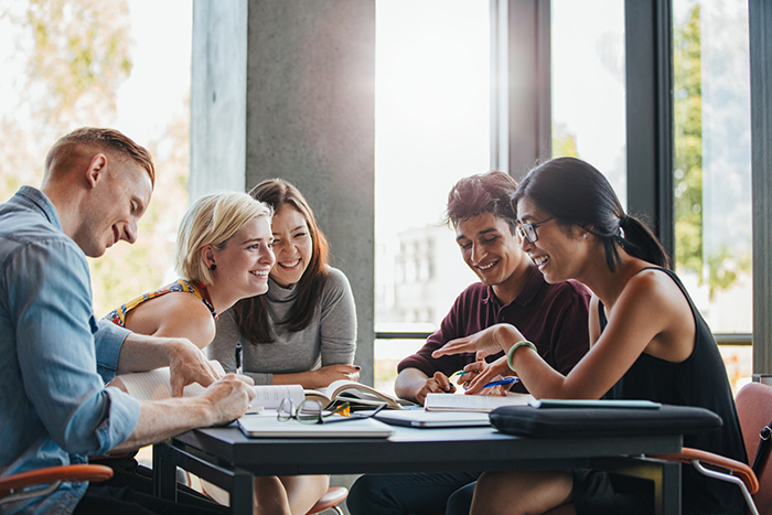 Group of people studying together at table with open books scattered on top