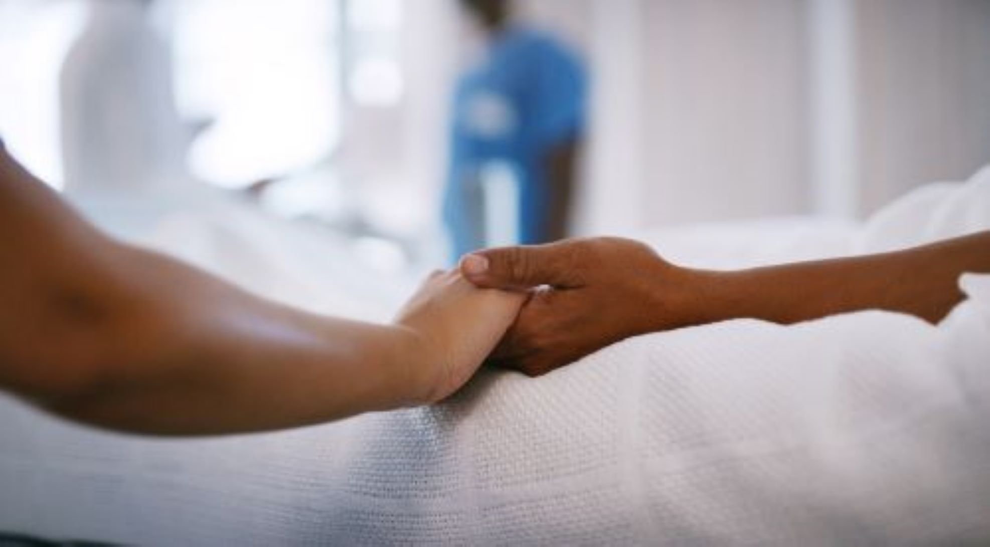 Image of someone holding hand of a person in a hospital bed