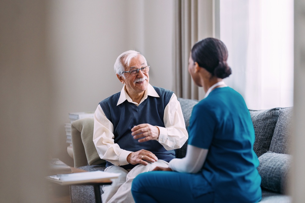 Older adult sitting on couch talking to OT practitioner
