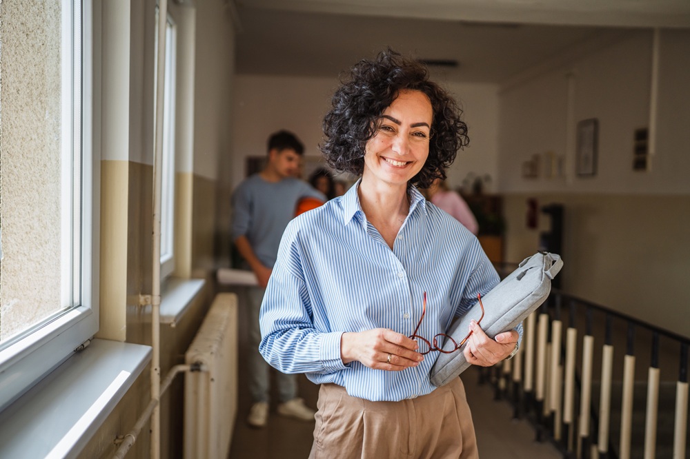 Smiling woman educator stands in hallway