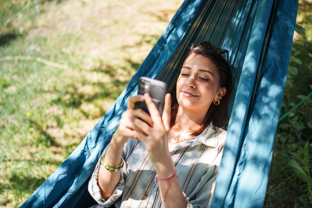 smiling woman in hammock looking at phone