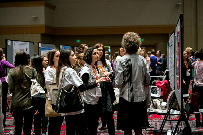 Group of people at poster session listening to presenter at AOTA Annual Conference and Expo