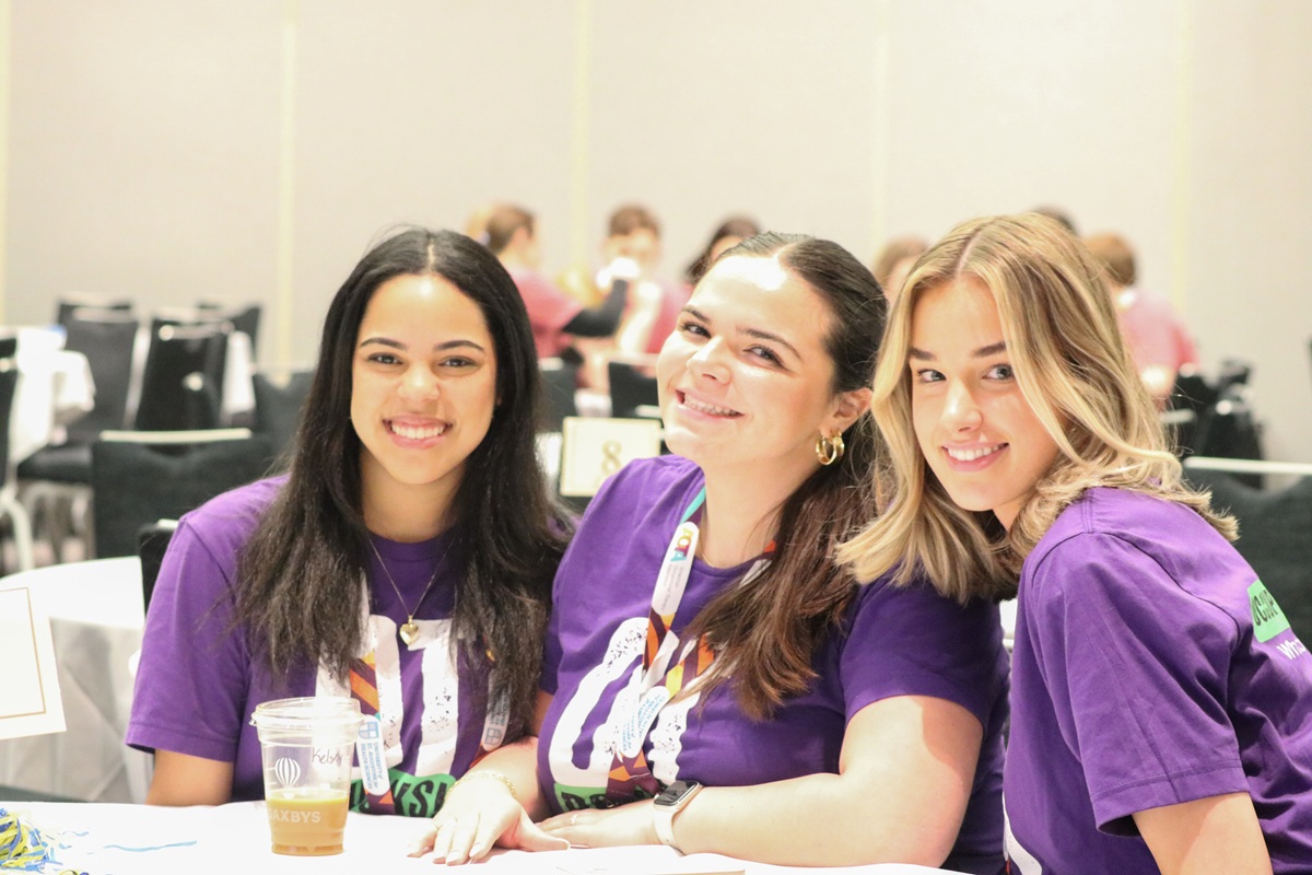 Three smiling people sit at a table at AOTA INSPIRE