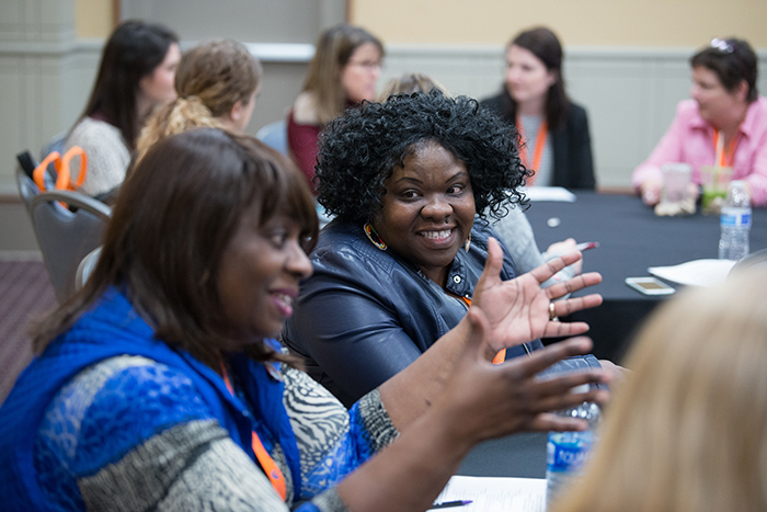 Smiling women at table talking during AOTA Annual Conference and Expo