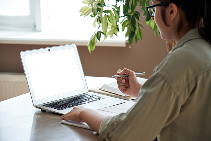 Woman at desk with laptop holding a pen