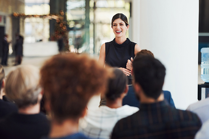 Professional woman standing in front of audience speaking during presentation
