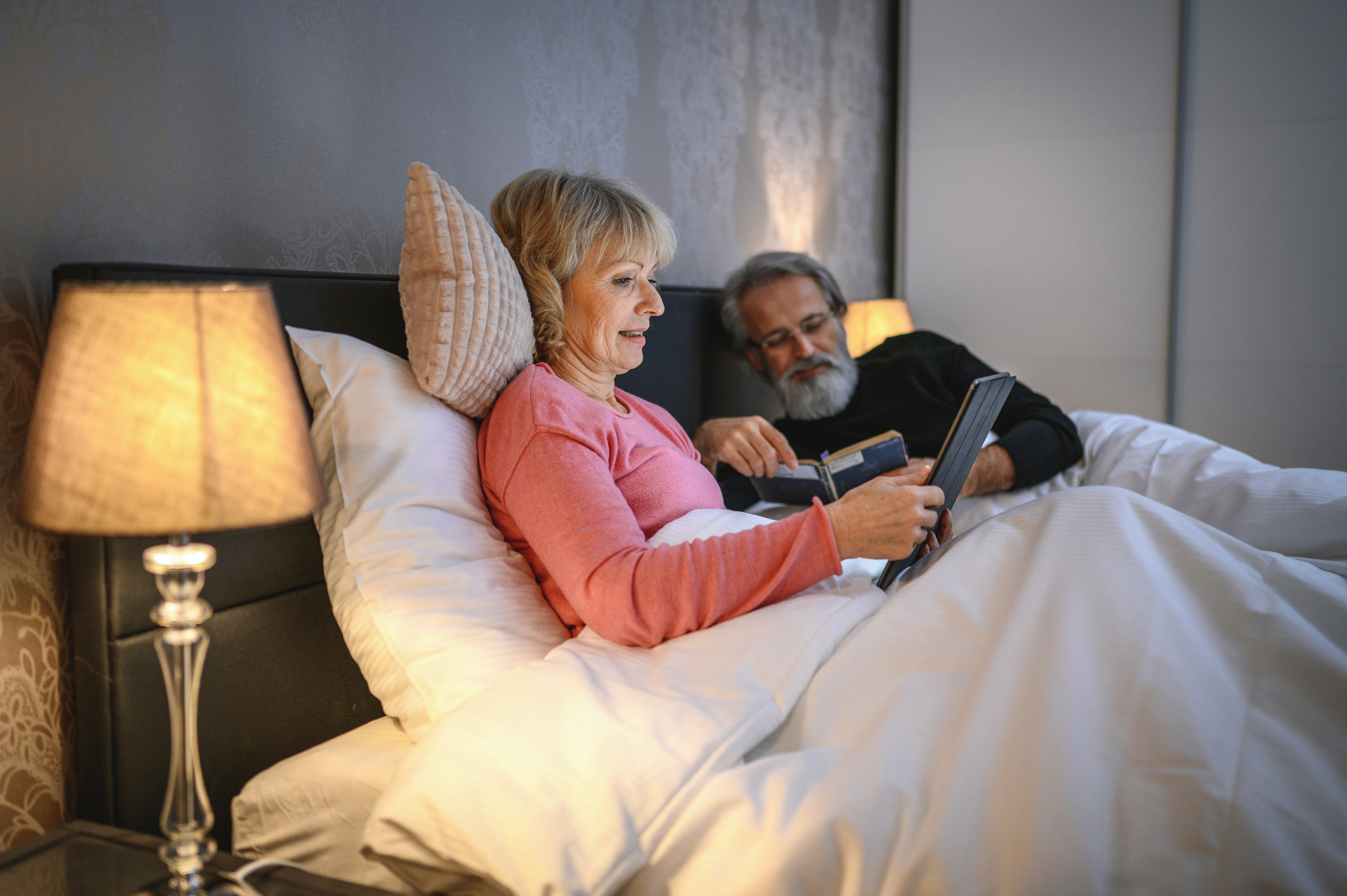 Two adults reading in bed