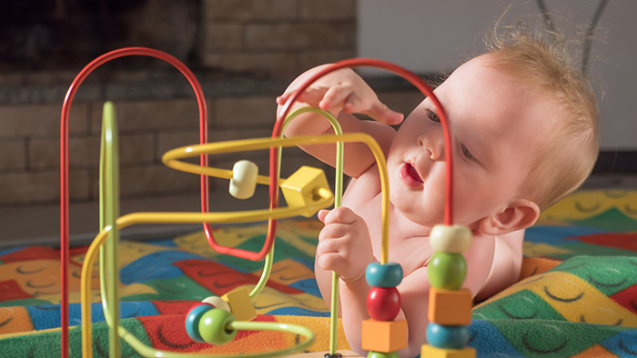 Baby laying on stomach on the floor playing with toy