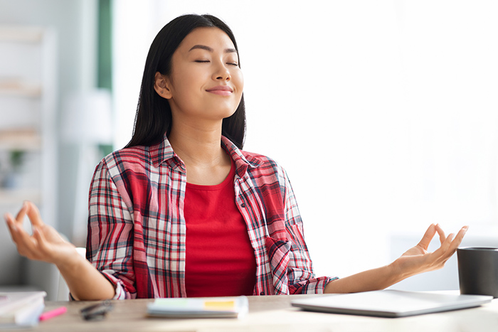 Woman with eyes closed meditating at desk
