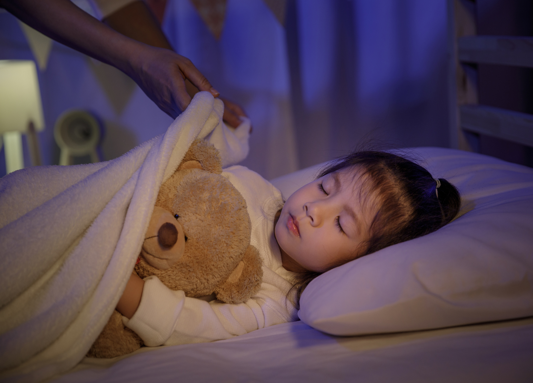 Child sleeping in bed with teddy bear