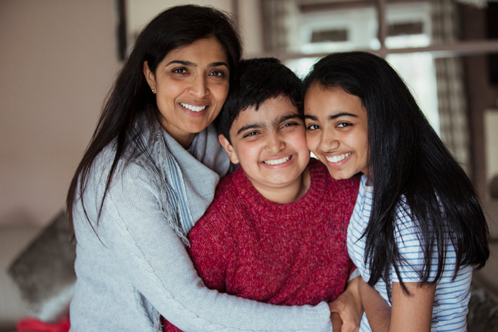 Mom smiling at camera hugging her son and daughter