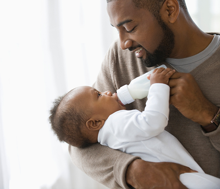 Father holding infant child and feeding with a bottle
