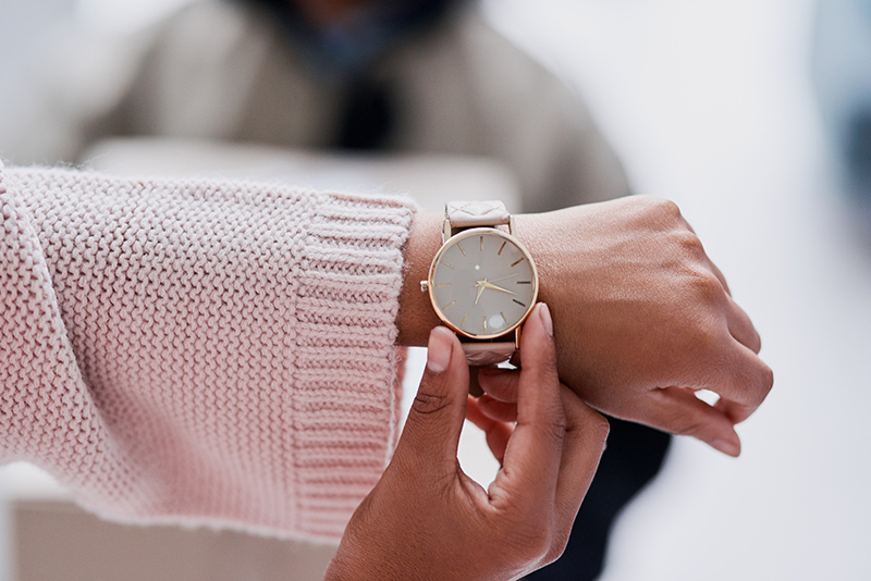 Female arm wearing wrist watch setting it with other hand