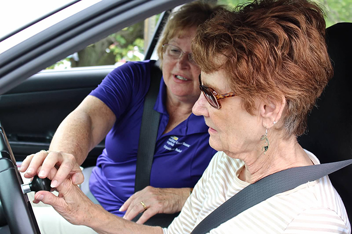 Female older driver working with occupational therapist and an adaptive steering wheel