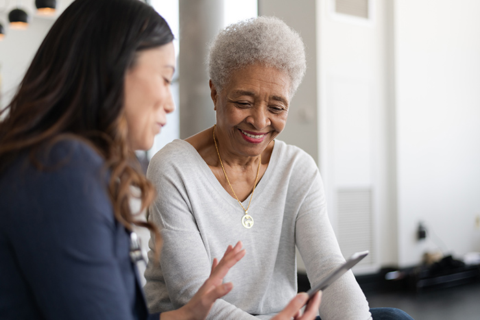 Female occupational therapist helping senior woman with tablet