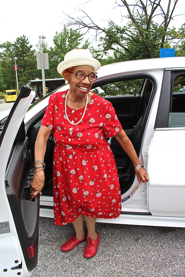 Senior woman getting out of car using grip bar 