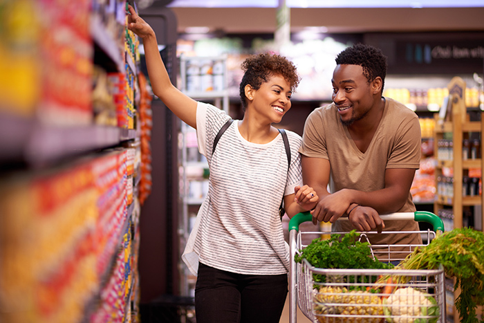 Smiling couple grocery shopping with cart full of fresh food
