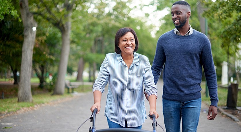 Man and senior woman using a walker outside walking down the street