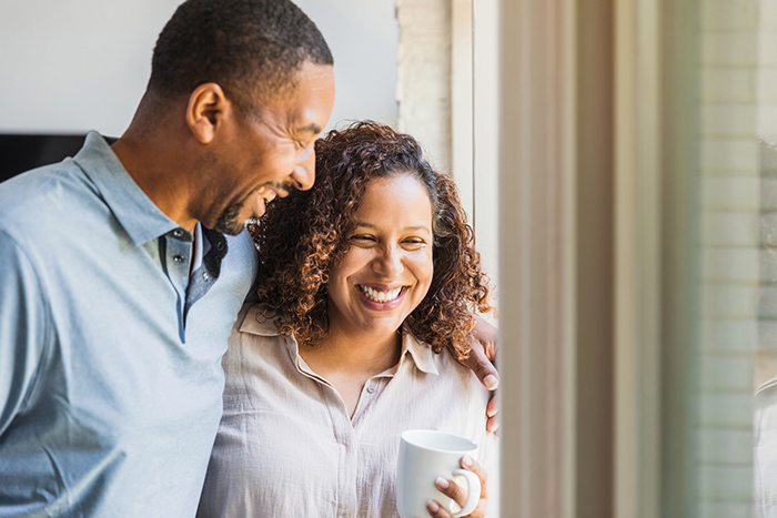 Smiling man with arm around woman drinking coffee