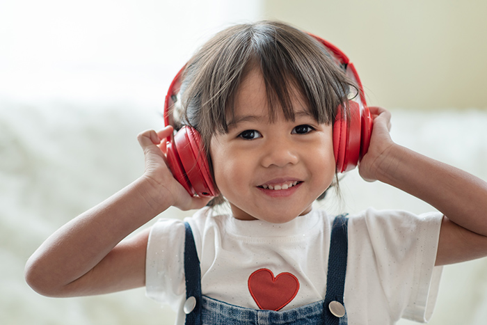 Young smiling girl wearing red headphones