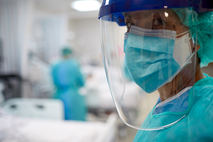 Close up of healthcare worker wearing mask and face shield in hospital room