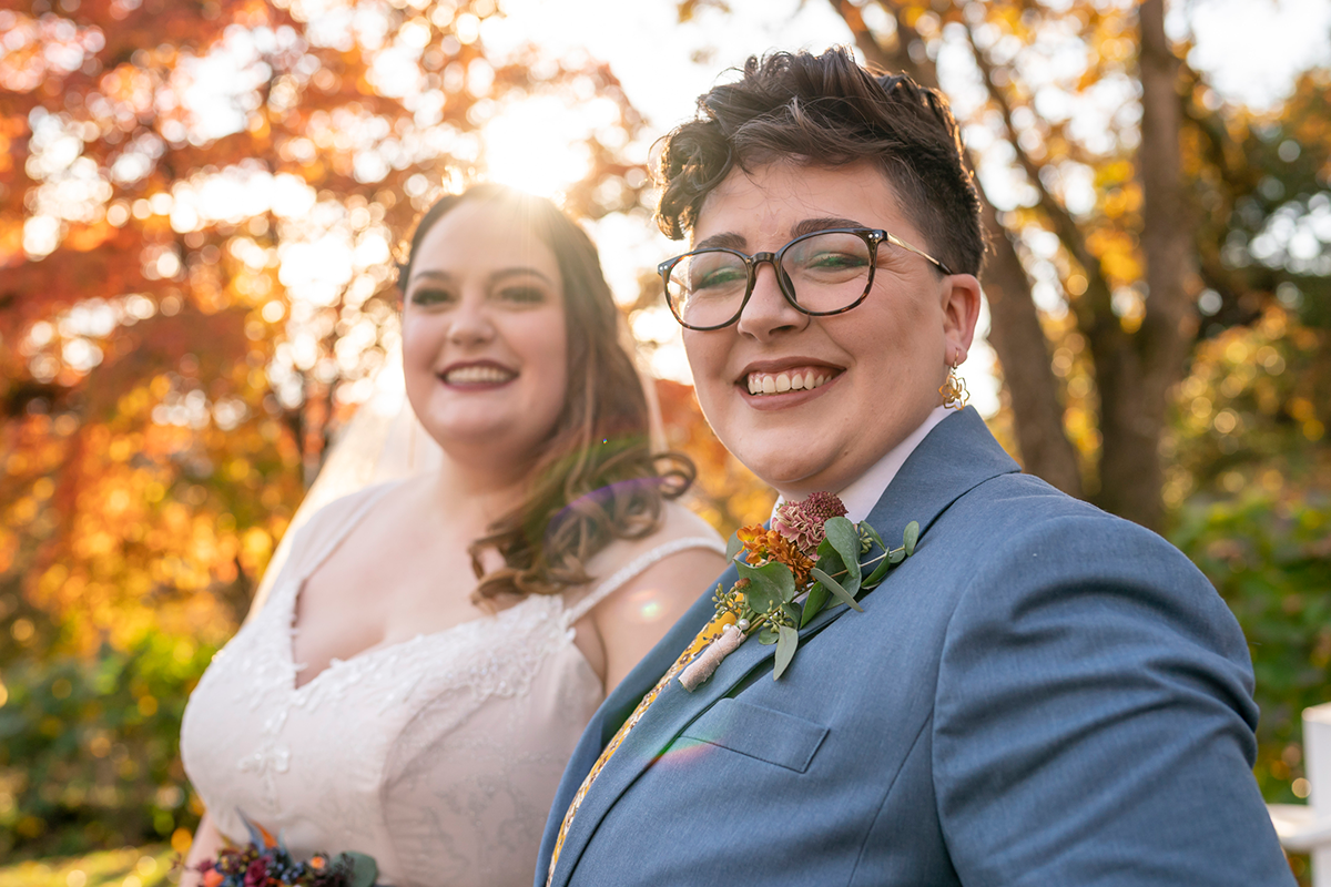 lgbtqia-smiling-couple-one-wearing-wedding-dress-other-wearing-suit
