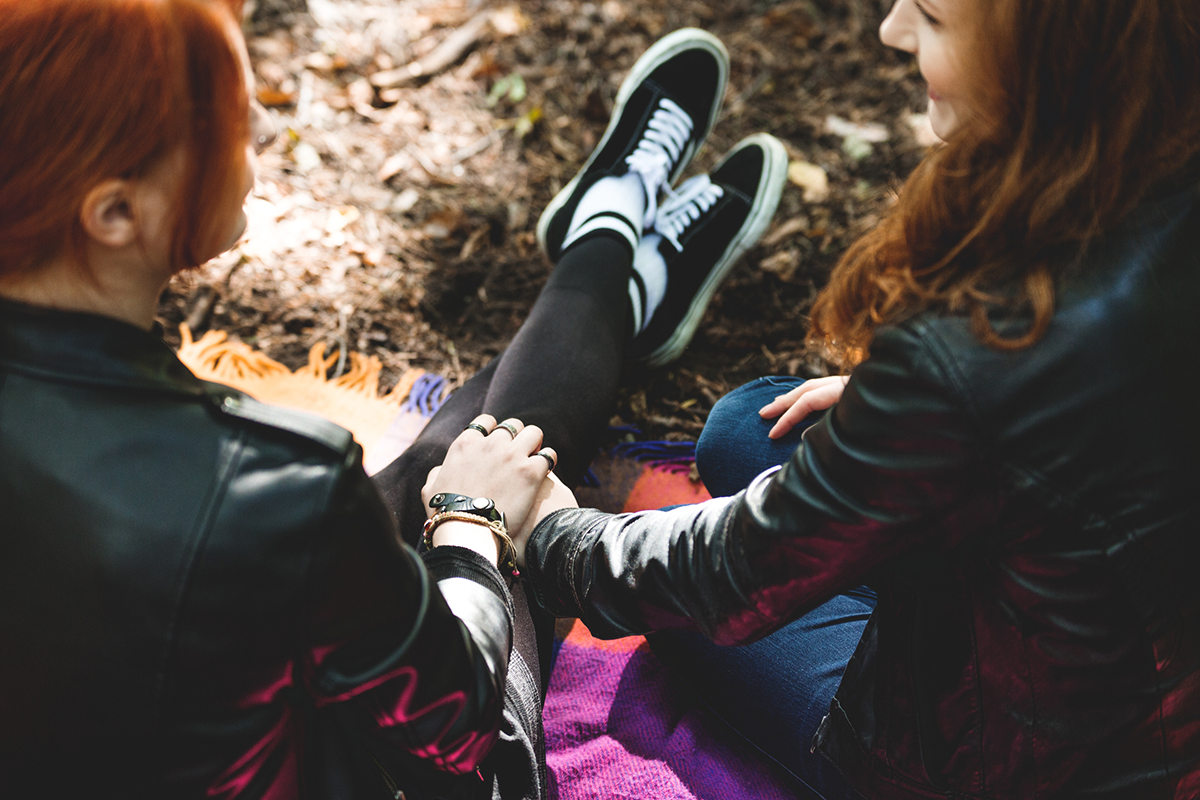 lgbtqia-two-teens-sitting-on-ground-outside-holding-hands
