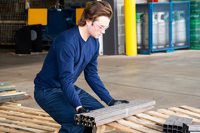 Man wearing gloves lifting heavy materials from palettes at warehouse