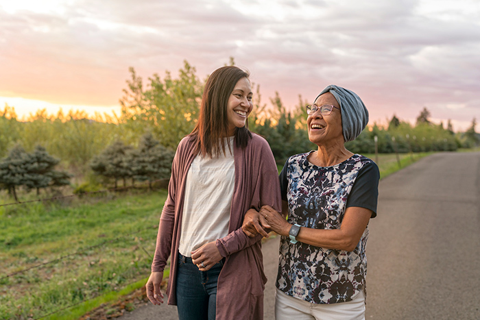 Woman walking outside with smiling senior woman wearing head wrap