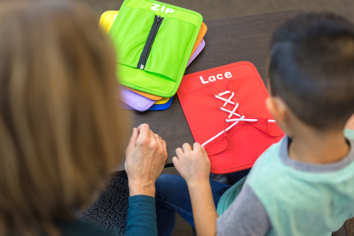 Woman helping young boy learn how to tie laces