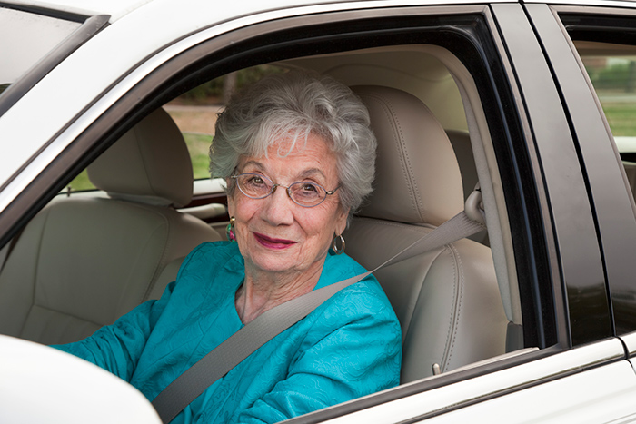 Female occupational therapist helping senior woman get out of bed and use walker