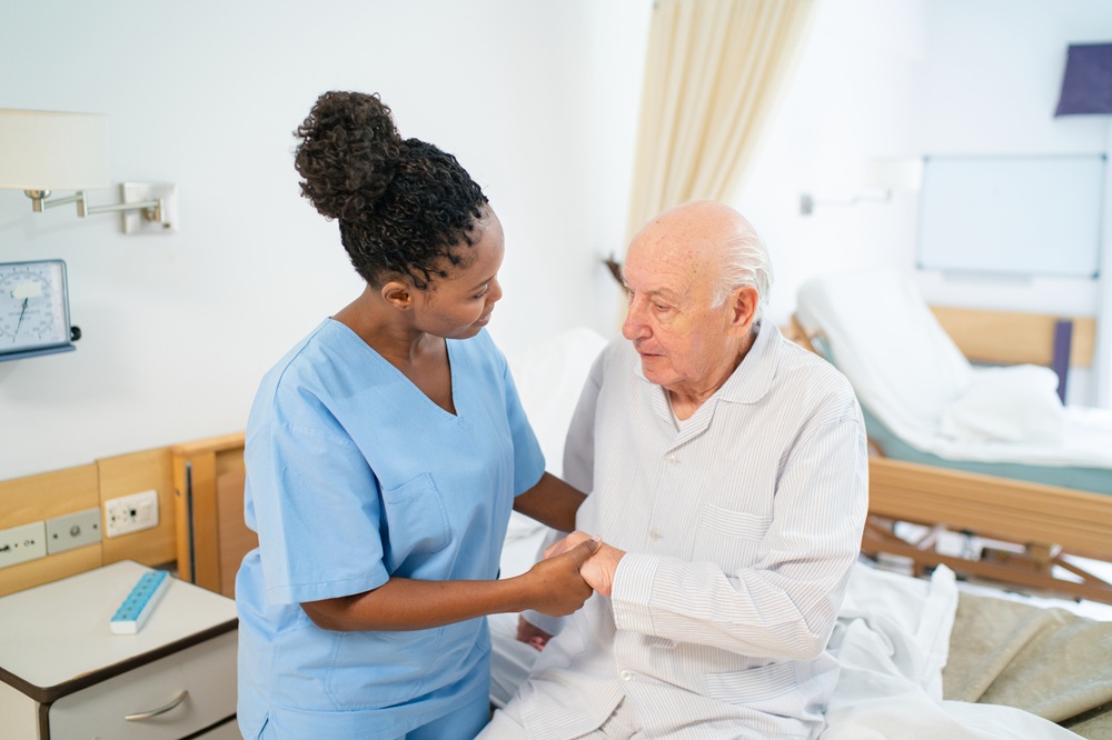 Practitioner helping senior man sitting in bed in a hospital setting